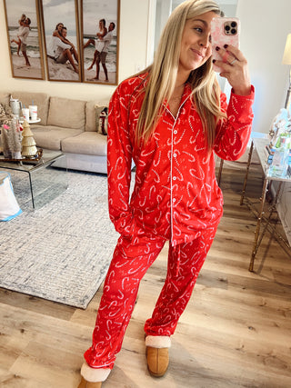 Person wearing a red pajama set with candy cane pattern in a living room.