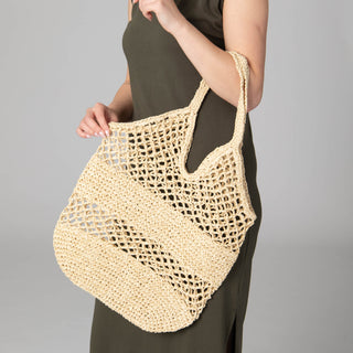 Model carrying a tan crochet tote bag. 