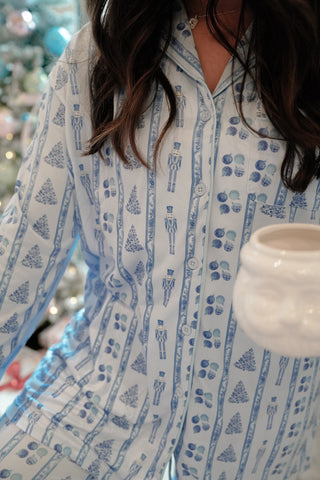 Person wearing a blue and white patterned shirt holding a white mug.