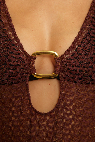 Close-up of a brown lace garment with a gold buckle.