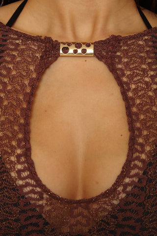 Brown lace top with a gold clasp on a dark background