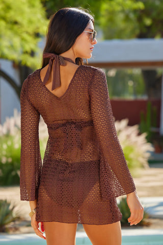 Woman wearing a brown lace dress with a blurred outdoor background