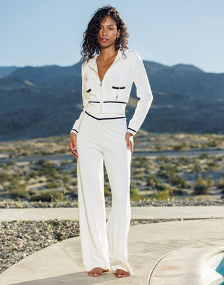 Woman in a white outfit standing in front of mountainous landscape