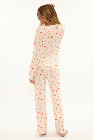 Person wearing a cream-colored onesie with red cherry pattern on a white background
