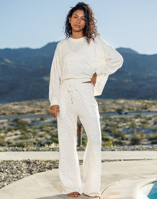Woman in a white outfit standing in a desert landscape with mountains in the background