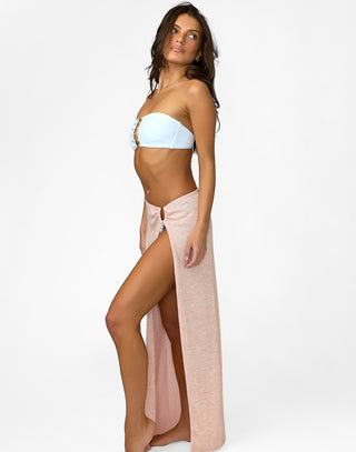Woman wearing a white bikini top and pink sarong on a white background