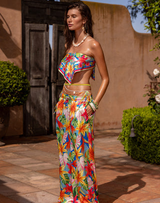 Woman wearing a colorful floral outfit standing outdoors.